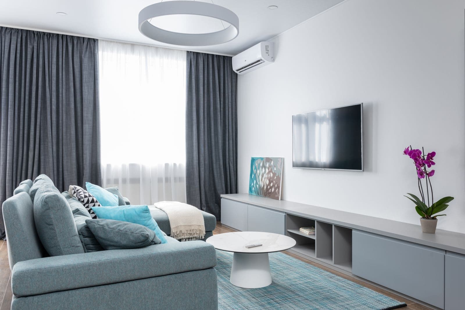 A wall-mounted television with a canvas artwork styled along a low console