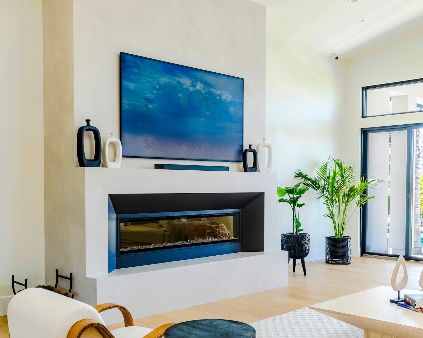 A large television mounted directly above a linear fireplace on a plaster feature wall