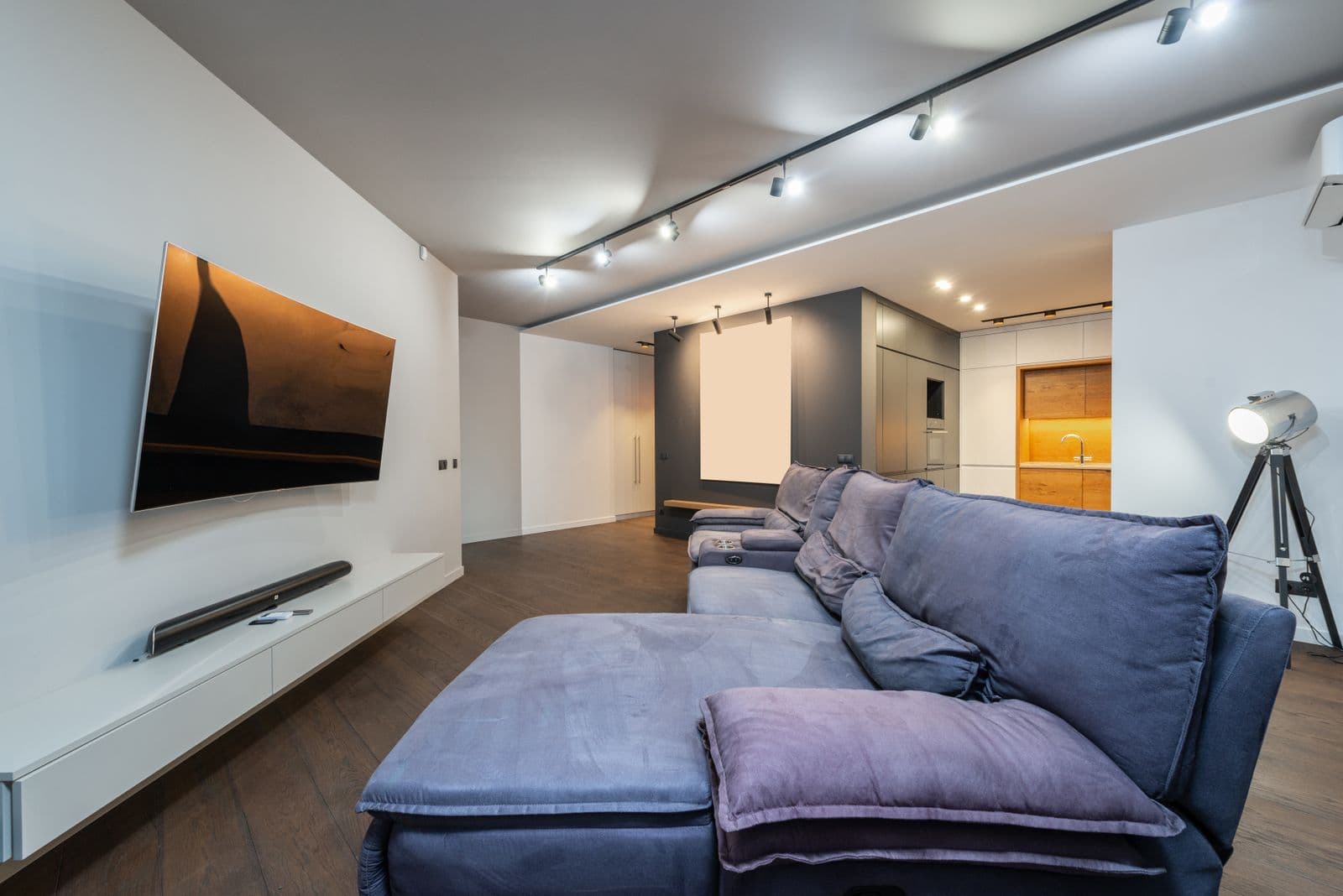 A curved television mounted above a floating white console with a soundbar
