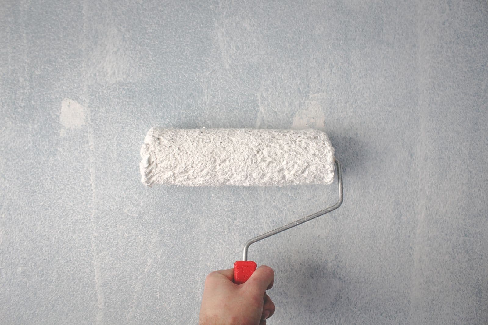 A paint roller mid-stroke refreshing a wall with a fresh coat of paint