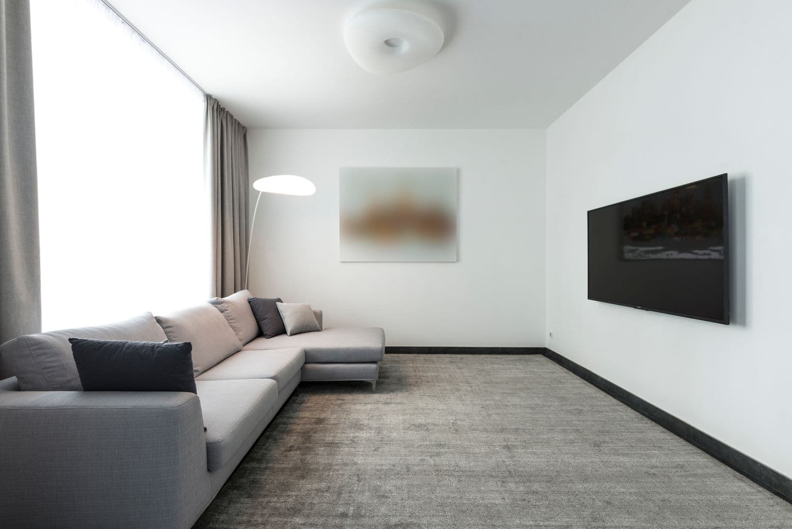 A minimalist living room with a wall-mounted television and no visible cables